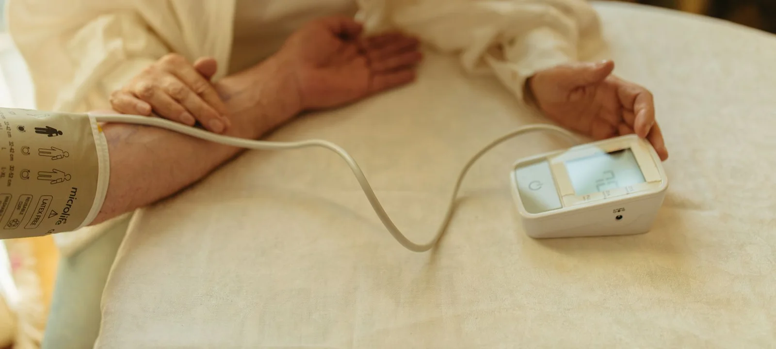 Pessoa medindo a pressão arterial com aparelho digital em casa